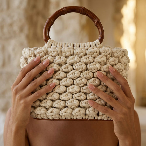 Beige woven handbag with wooden handle held by a person against a blurred background