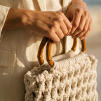 ZAWJIEN Riviera Bag - Close-up of hands holding a beige woven bag with wooden handles.