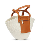 Woven bag with brown leather straps and pocket on a white background